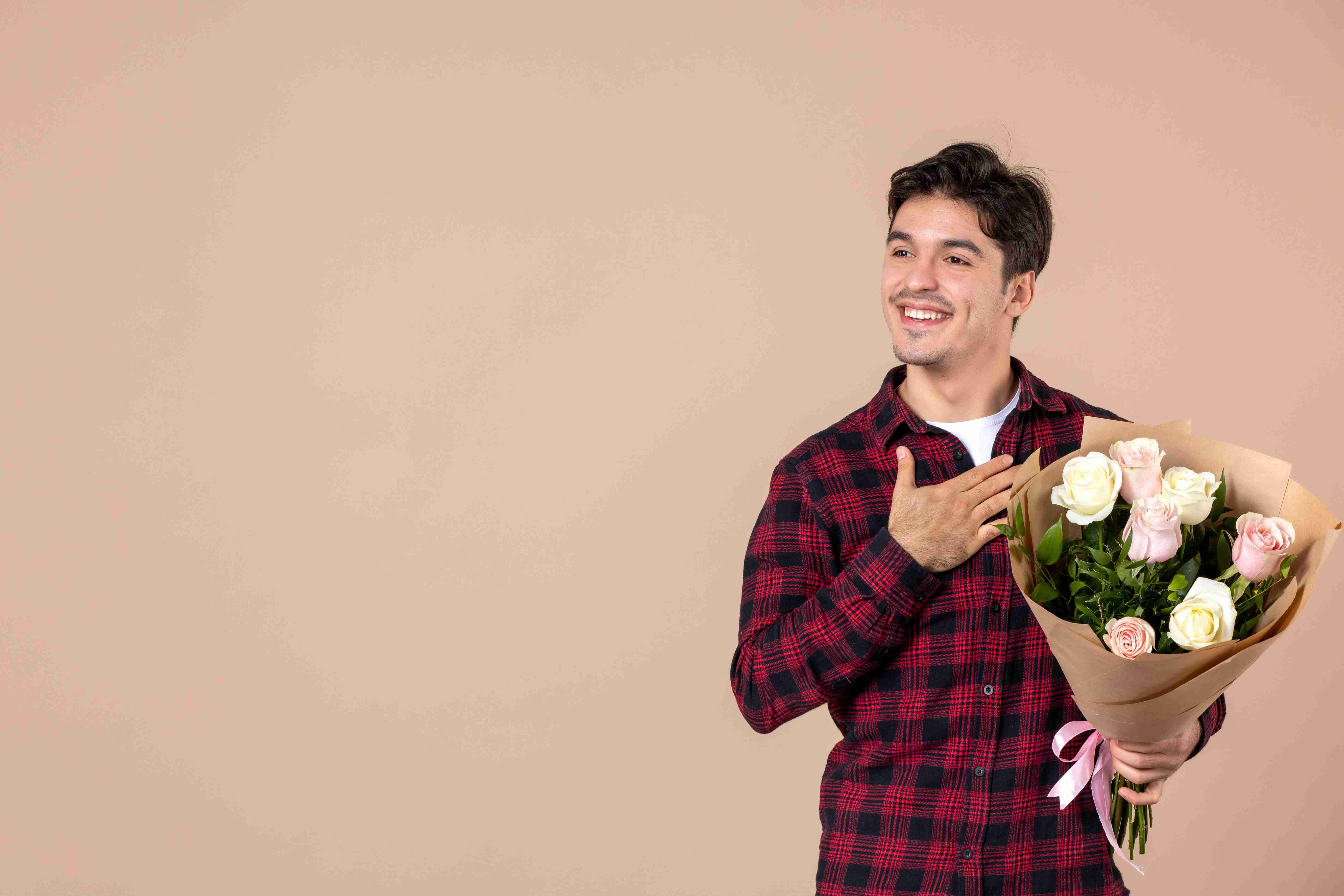 Man holding a bouquet of flowers against a brown wall
